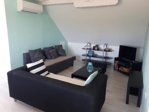 a living room with a black couch and a tv at The Olive Garden in Šibenik