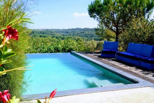 a swimming pool with two blue chairs next to it at Private Villa with pool and magnificent view in Ceissa