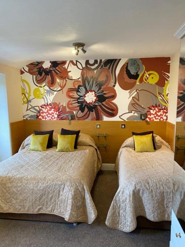 a bedroom with two beds and a flower mural at Park Manor Hotel in Scarborough