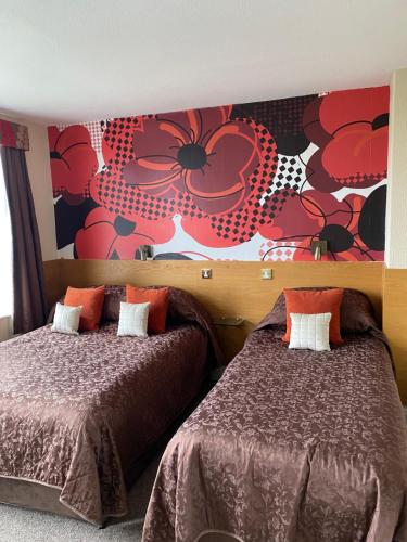 a bedroom with two beds and a flower mural at Park Manor Hotel in Scarborough
