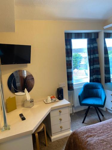 a hotel room with a desk and a blue chair at Park Manor Hotel in Scarborough