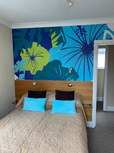 a bedroom with a large bed with blue and yellow flowers on the wall at Park Manor Hotel in Scarborough