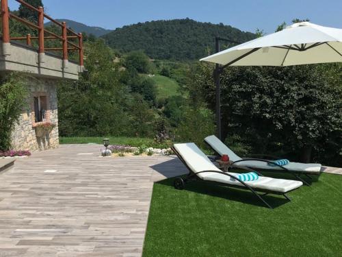 two lounge chairs and an umbrella on the grass at LE LANTERNE in Villa dʼAlmè
