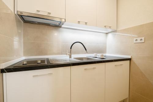 una cocina con armarios blancos y fregadero en Apartmani Vuletić en Neum