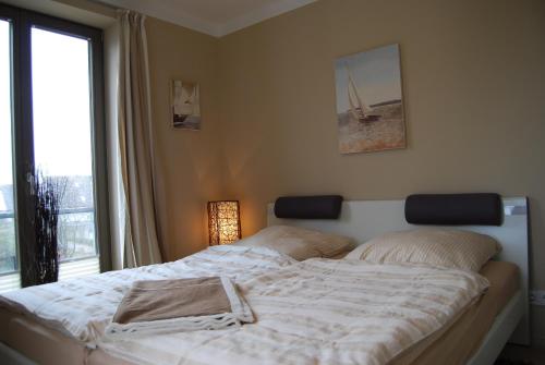 ein Bett in einem Schlafzimmer mit einem großen Fenster in der Unterkunft Luxuswohnung Abendsonne in Wenningstedt-Braderup