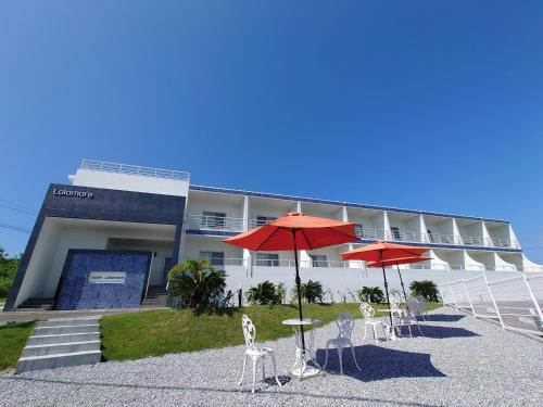 two red umbrellas and chairs in front of a building at Lalamare Kouri in Nakijin