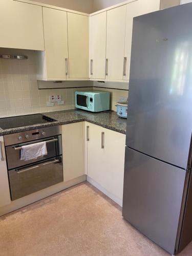 a kitchen with a refrigerator and a microwave at Beautiful Bexhill Cottage with garden 3 mins walk to beach in Bexhill