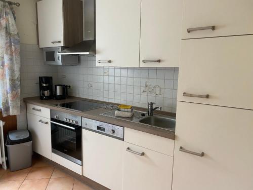 a kitchen with white cabinets and a sink at Hotel Meereswoge in Cuxhaven