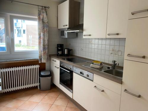a kitchen with a stove top oven and a sink at Hotel Meereswoge in Cuxhaven