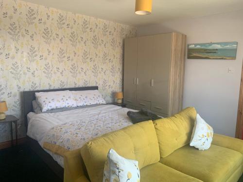 a bedroom with a bed and a yellow couch at Mussenden House in Articlave