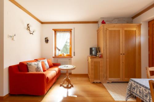 a living room with a red couch and a table at Antico brolo Mountain lodge in Gallio