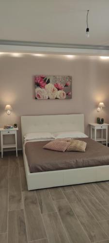 1 cama en un dormitorio con 2 mesas y 2 flores en Francesco en Castellabate
