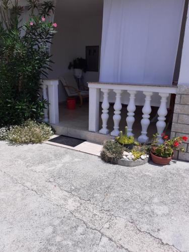 a porch with a white railing and some plants at Dvosobni apartman in Banjol