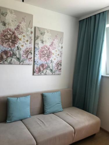 a couch in a living room with two paintings on the wall at Apartament Maria in Gietrzwałd