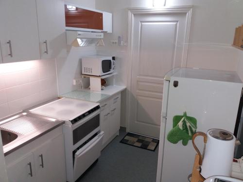 Il comprend une petite cuisine blanche équipée d'un four micro-ondes et d'un réfrigérateur. dans l'établissement Château de Locquéran, à Plouhinec