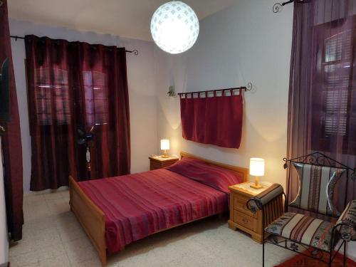 a bedroom with a red bed and a chair at chambre Noix de Coco résidence Chahrazad in Sfax