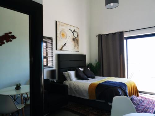 a bedroom with a bed and a table and a window at Relax,Revive,Reset & enjoy the sounds of the sea! in Cape Town