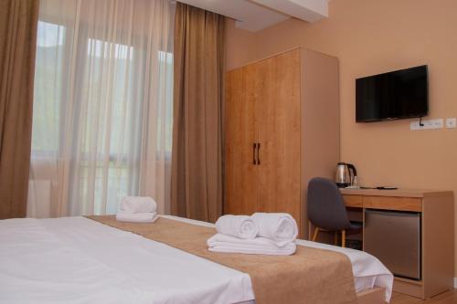 a hotel room with a bed and a desk with towels at Likani Home in Borjomi