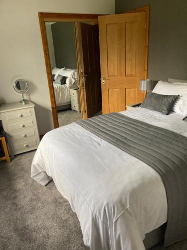 a bedroom with a large white bed and a mirror at Mayfield B&B in Fort William