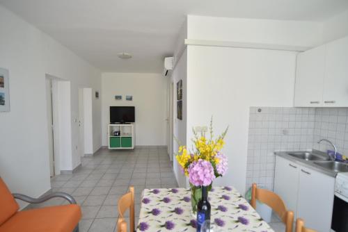 eine Küche mit einem Tisch und einer Blumenvase darauf in der Unterkunft Apartmani Badurina - Maslina in Lun
