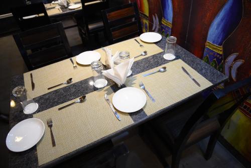 a table with white plates and silverware on it at Broadway Inn in Jaipur
