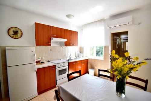 a kitchen with a table and a white refrigerator at Apartmani Badurina - Crnika in Lun