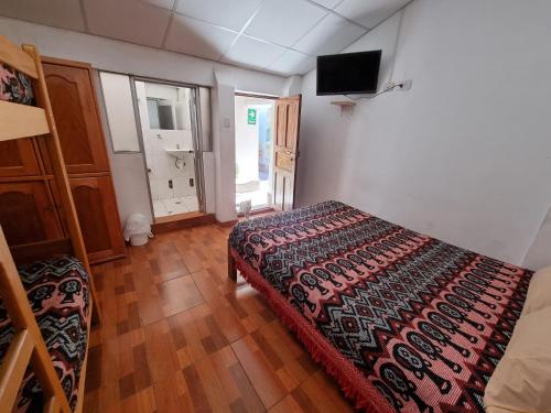 a bedroom with a bed and a television on the wall at Chelitos Backpacker in Cusco