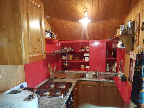 uma pequena cozinha com um lavatório e paredes vermelhas em Le Chalet n 0082 em La Thuile