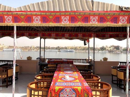 a dining room table with chairs and umbrellas at Nile Castle in Luxor