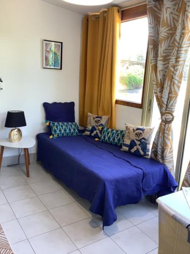 een slaapkamer met een blauw bed en een raam bij Charmant Appartement 2 pièces in Eccica-Suarella