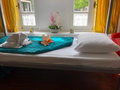 ein Bett mit zwei Handtüchern drauf mit zwei Fenstern in der Unterkunft Room Mate Hostel Amsterdam Zaandam in Zaandam