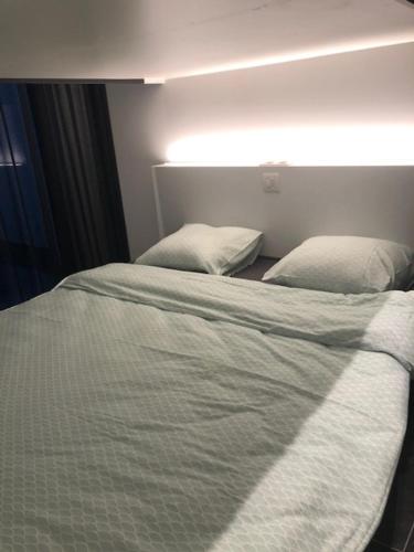 ein weißes Bett mit zwei Kissen in einem Zimmer in der Unterkunft bloc79/zero in Knokke-Heist