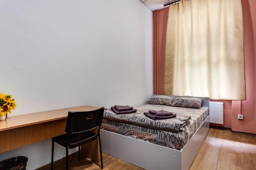 a small bedroom with a bed and a desk and a table at Mister Hostel in Lviv