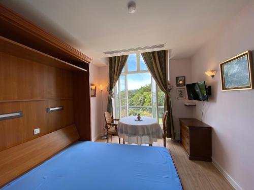 une chambre avec un lit, une table et une fenêtre dans l'établissement Château de Locquéran, à Plouhinec