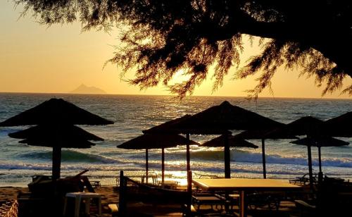 a group of tables and umbrellas on a beach at Galini Apartments Ideal for family near the beach in Kalamaki Heraklion