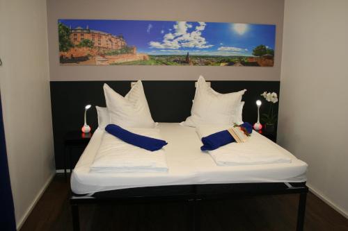 een bed met witte lakens en blauwe kussens erop bij Mar Hotel in Marburg an der Lahn