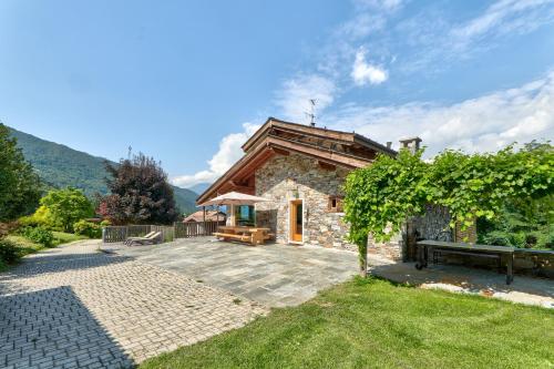 a small stone house with a bench in a yard at chalet con piscina e vista panoramica in Colico