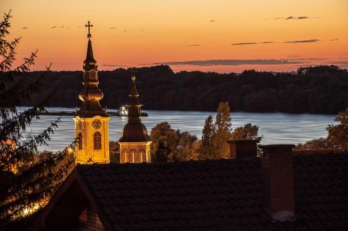 a church with a clock tower at sunset at Sakota family house in Sremska Kamenica