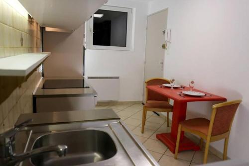 - une cuisine avec un évier, une table rouge et des chaises dans l'établissement Maison Rurale En Bordure De Forêt, à Schirmeck