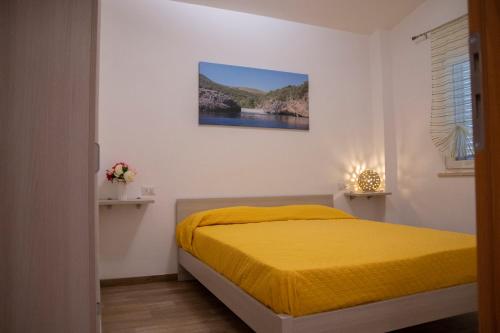 a bedroom with a yellow bed and a painting on the wall at Il Mirto Residence in Marina di Camerota