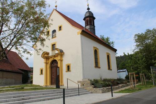 a small white church with a steeple on a street at Ferienwohnung Forellenhof in Handthal