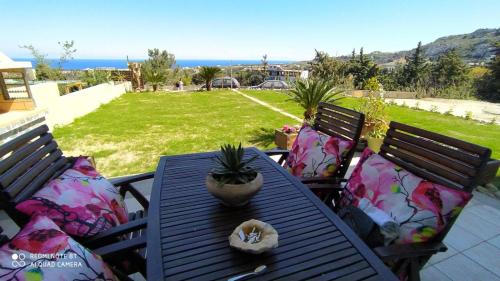 a patio table with pillows and a potted plant on it at Luxury Apartment with Sea View near Kallithea in Koskinou