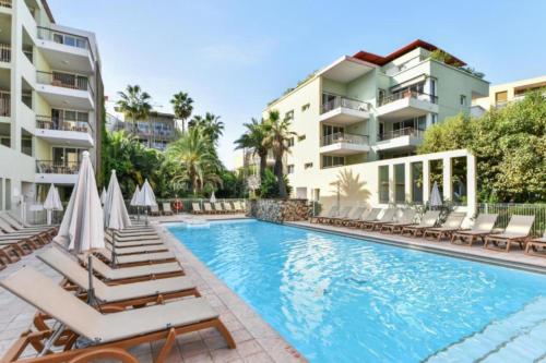 une piscine avec des chaises longues et un complexe hôtelier dans l'établissement Appartement Port Prestige - terrasse - piscine - parking, à Antibes