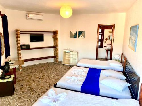 a hotel room with three beds and a television at Hotel e Pousada Cumbuco Guesthouse in Cumbuco