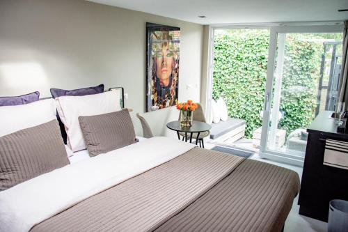 Un dormitorio con una cama grande y una ventana en Petite Maison Bennebroek en Bennebroek