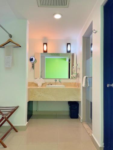 a bathroom with a sink and a green mirror at Seven Crown Express & Suites by Kavia in Cabo San Lucas