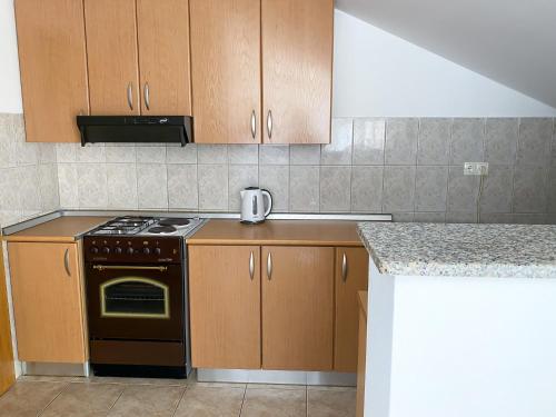 uma cozinha com armários de madeira e um forno com placa de fogão em Maslina Apartments em Široki Brijeg