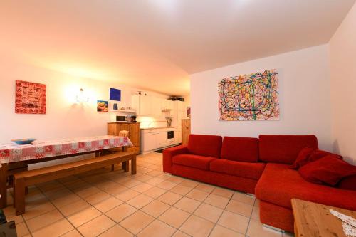 een woonkamer met een rode bank en een keuken bij Bosco Gurin Nature & Ski in Bosco Gurin