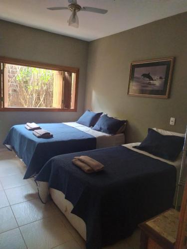 1 dormitorio con 2 camas con sábanas azules y ventana en Casa Verde en Pirenópolis