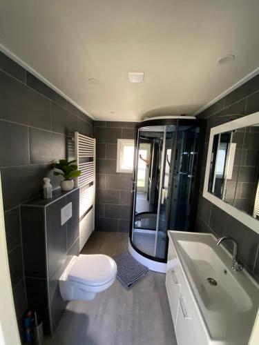 a bathroom with a toilet and a tub and a sink at Luxe Chalet 146 in Putten